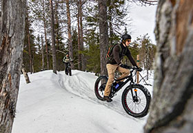 Kaksi maastopyöräilijää ajaa perätysten polkua pitkin talvimaisemassa. Kuva Johanna Kalliomäki.